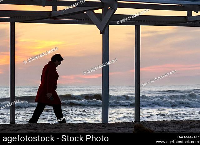 RUSSIA, REPUBLIC OF CRIMEA - DECEMBER 3, 2023: A person is seen on a beach in the city of Yevpatoria on Crimea's Black Sea coast at sunset in winter