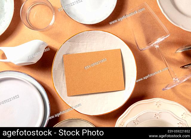 Invitaion mockup, overhead flat lay shot with tableware on a rustic background. RSVP card, shot from the top on a plate, with glasses and a place for text