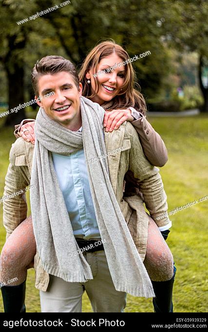 Young caucasian couple in love piggybacking at a park in austria in autumn