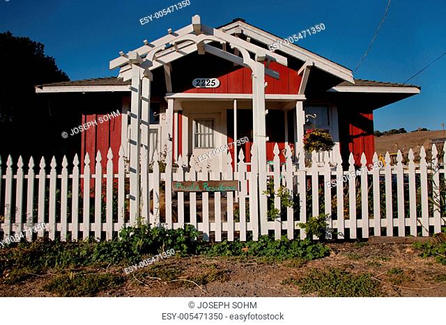 A small red house with White Picket fence and sign saying Private Residence, Harmony, CA, the central coast of California
