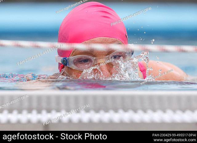 28 April 2023, North Rhine-Westphalia, Paderborn: A swimmer wearing goggles swims at the Rolandsbad outdoor pool at the start of the outdoor pool season in...