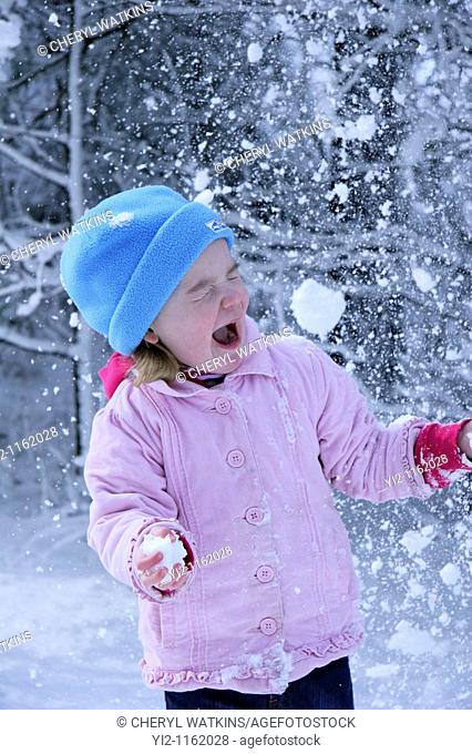 girl playing in the snow with a snowball headed towards her