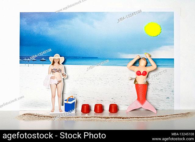 young woman in bikini stands on the beach, bath towel and sunglasses in hand, plastic bathing mermaid worships the sun, cool box and red container stand between...