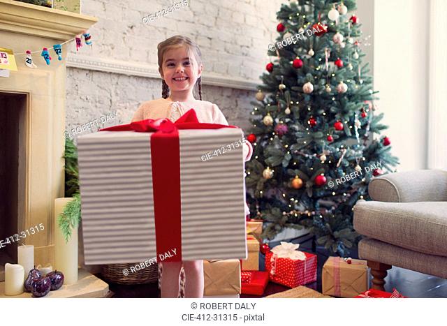 Portrait enthusiastic girl holding large Christmas gift
