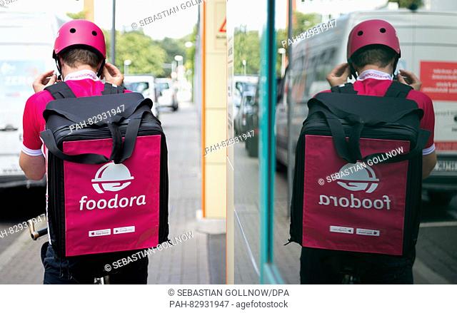 Bike courier Anton from Foodora puts on his helmet in Hanover, Germany, 18 August 2016. .PHOTO: SEBASTIAN GOLLNOW/DPA | usage worldwide