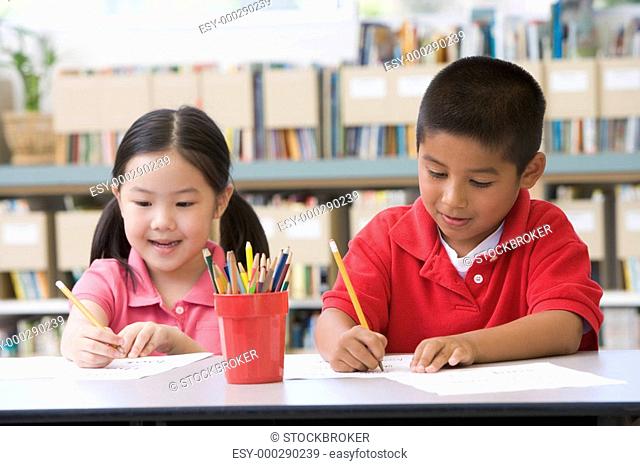 Two students in class writing