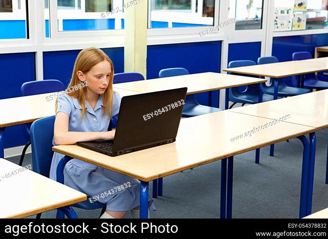Primary school caucasian girl using a laptop in an empty classroom