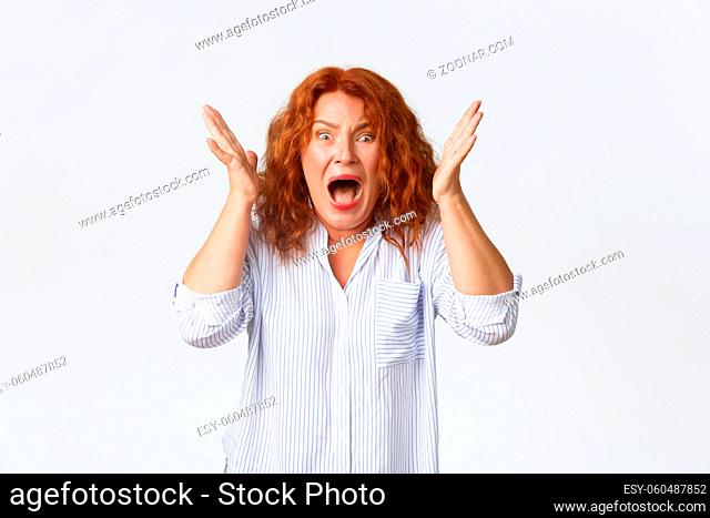 Troubled and frustrated redhead middle-aged woman grab head in denial and grimassing, starting to panic, reacti to bad news, facing terrible situation