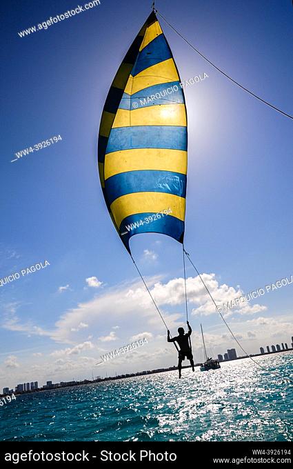 Tourist enjoying his ride on a kind of kite with seat over the turquoise sea near Cancun, Mexico
