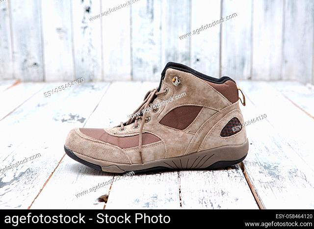 Footwear concept. A brown men#39;s boot represented on wooden background. A boot with shoe-string sands