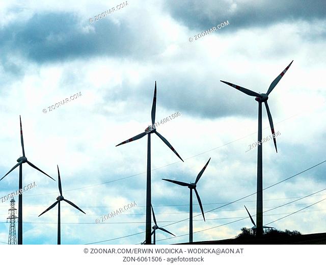 Windräder und Strommasten in einem Windpark. Wind-Kraftwerk für erneuerbare Energie