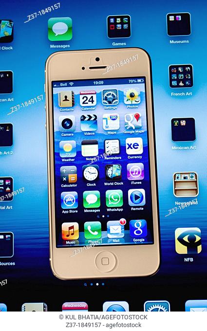 An Iphone 5 rests on top of an Ipad 3, showing various Apps on the Retina screens, Canada Some icons appear on both devices