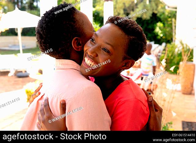 Senior African American woman embracing with her daughter during a family lunch in the garden