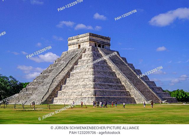 Tourists walk in front of the impressive pyramid in the ruined city of Chichén Itza. The pyramid of Kukulcan and most of the other buildings of Chichén Itza...
