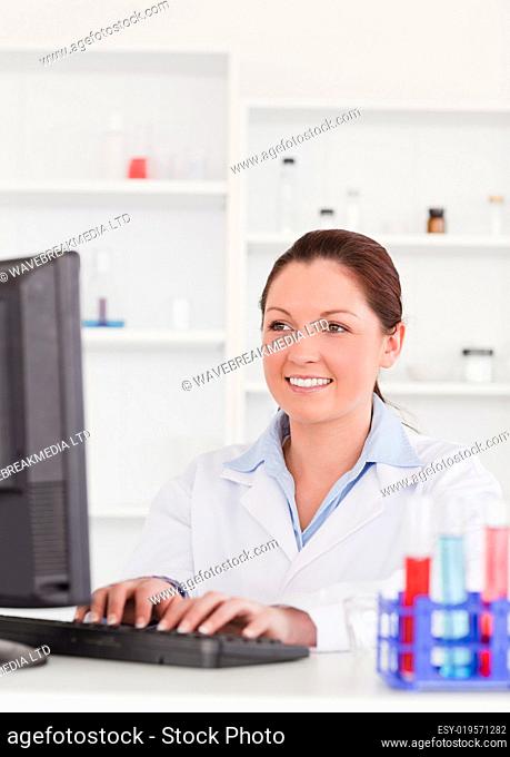 Smiling scientist typing a report with her computer