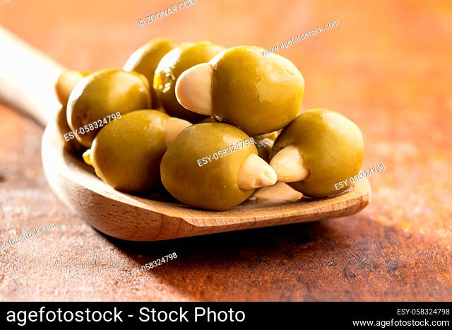 Pitted green olives stuffed with almonds on wooden spoon on wooden table