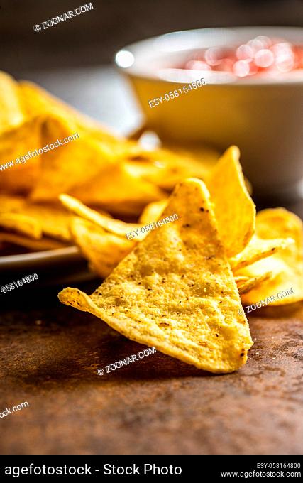Tortilla chips and red tomato salsa dip. Mexican nacho chips on brown table