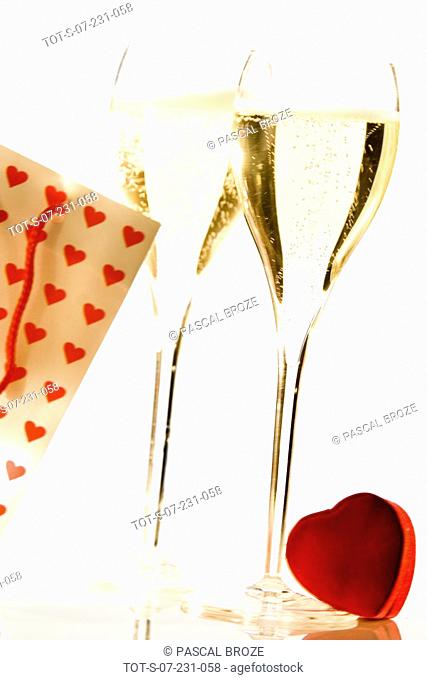 Close-up of two champagne flutes with a heart and a gift bag
