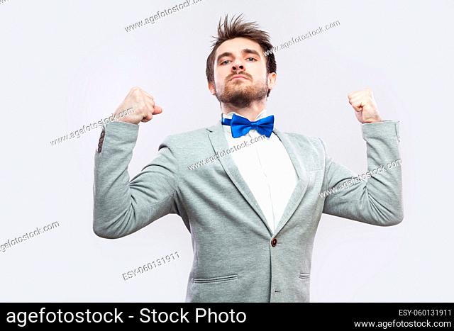 I am strong and independent. Portrait of satisfied proud handsome bearded man in casual grey suit and blue bow tie standing and looking at camera