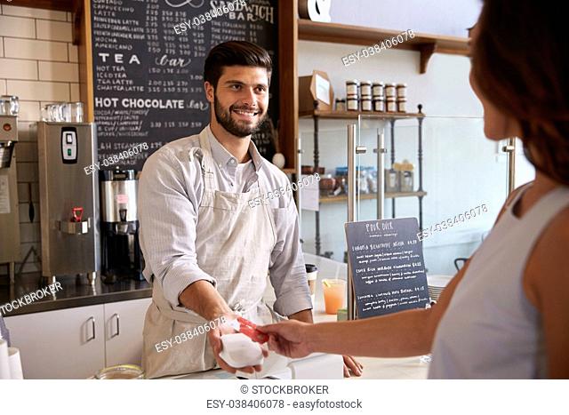 Barista taking card payment from a customer at a coffee shop
