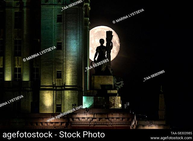 RUSSIA, MOSCOW - APRIL 8, 2023: A view of a sculpture on the Main Building of Lomonosov Moscow State University with the moon in the background