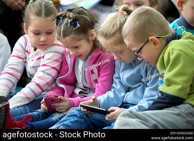 Belarus, Gomel, November 2, 2017. Opening of children's library.Little girl is looking into a cell phone. Little girl is playing in a cell phone