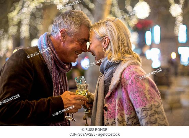Mature couple making a champagne toast on tree lined avenue at xmas, Majorca, Spain