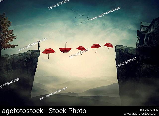 The way back home with a person on the edge of a cliff planning to pass the abyss by stepping on the floating umbrellas. Surreal scene with flying umbrella like...