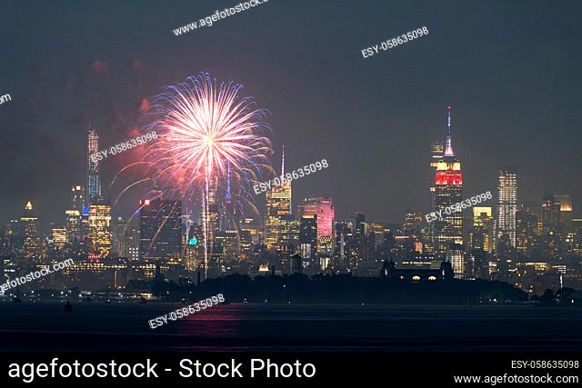 Fireworks are being set off from barges on the river between Jersey City and New York