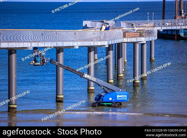 22 October 2020, Mecklenburg-Western Pomerania, Koserow: Construction workers are working from an elevating platform on the new pier on the beach of the island...