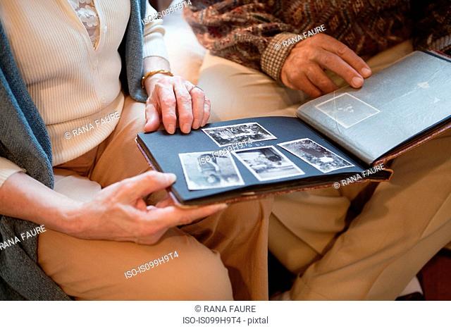 Senior couple looking through photo album, mid section