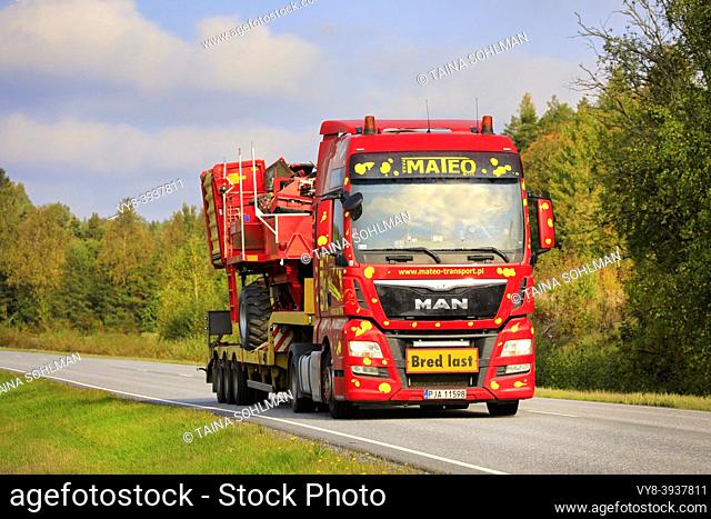 Colorful MAN TGX truck of Mateo Transport hauls Grimme SE 75-30 potato harvester as wide load on a beautiful day of autumn. Salo, Finland. Sept 25, 20
