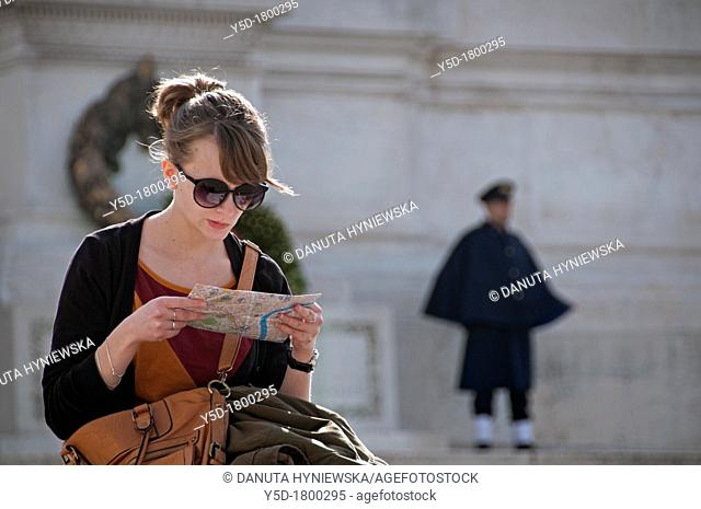 young woman studing map, Piazza Venezia, Rome, Italy, in the background National memorial of King Viktor Emanuel II, Vittoriano