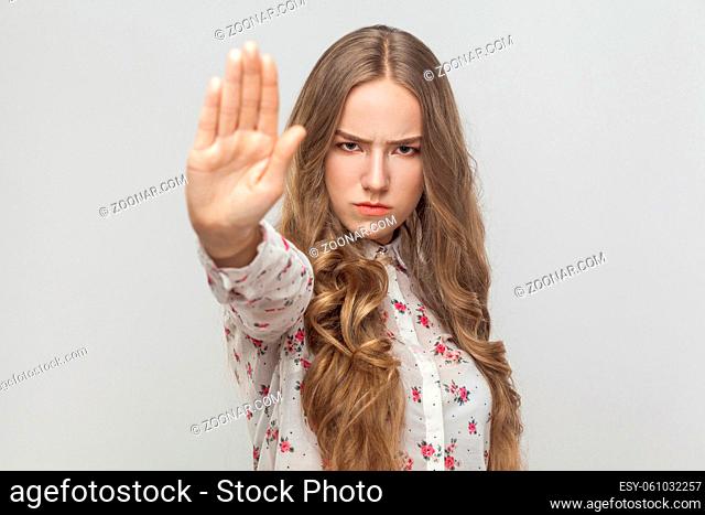 Stop! Rage young woman showing no sign. Studio shot, gray background