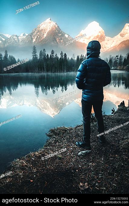male Hiker standing at Mountain Lake watching the Sunrise in Austria - schiederweiher