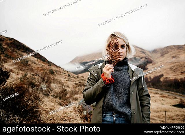 UK, Scotland, Highland, portrait of young woman holding fern