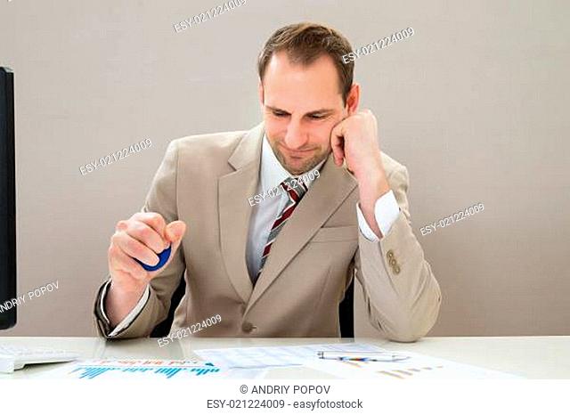 Businessman Squeezing Blue Stress Ball At Desk