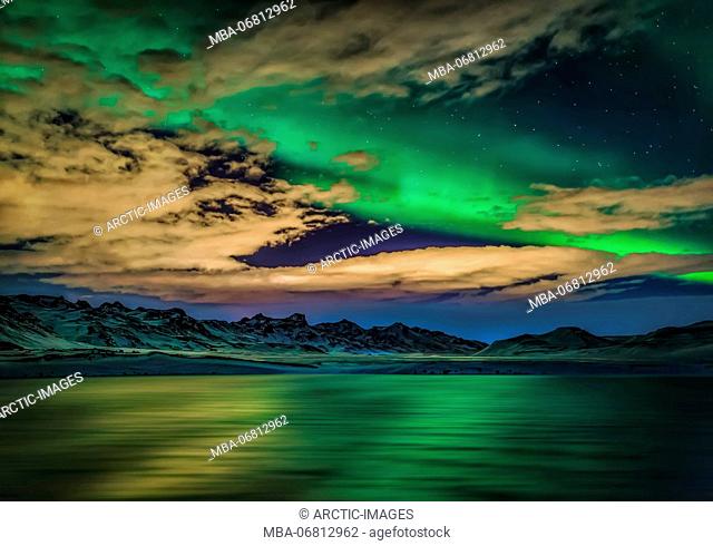 Aurora Borealis over Lake Kleifarvatn, Iceland. Cloudy evening with northern lights reflecting on the lake