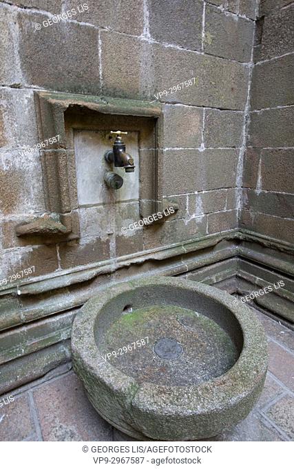 Stone fountain and big brass tap faucet inside Mont Saint Michel. Normandy, France
