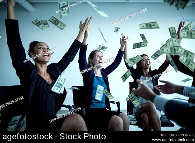 Business people with arms raised throwing money in the air