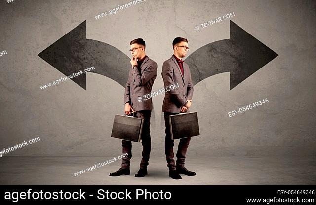 Young conflicted businessman choosing between two directions represented by black arrows