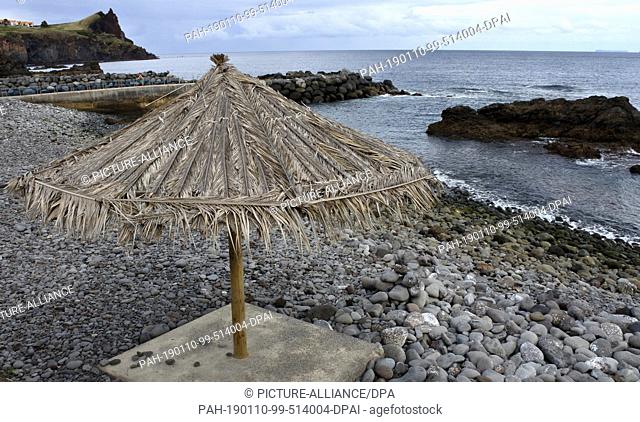 21 November 2018, Portugal, Caniço De Baixo: A straw parasol stands on the coastal promenade in Caniço de Baixo on the Portuguese island of Madeira