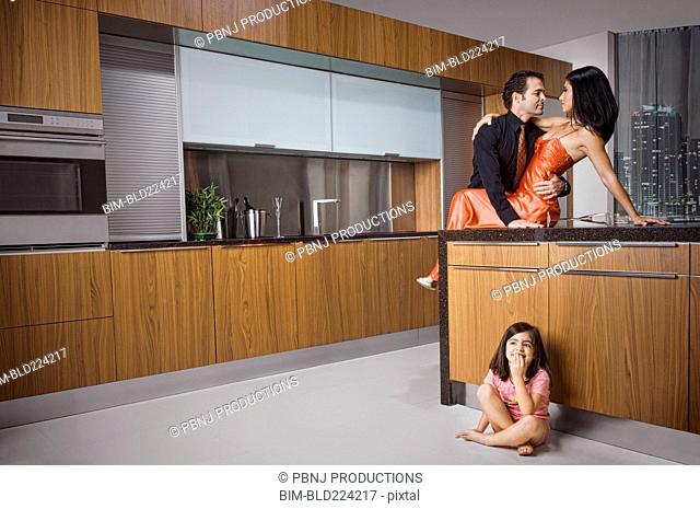 Caucasian girl eavesdropping on parents in kitchen