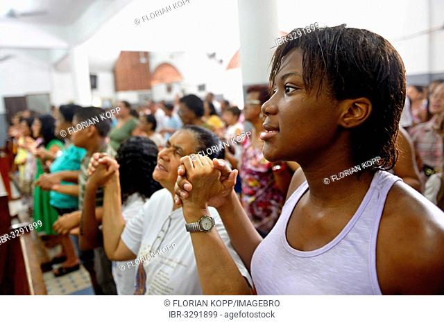 Worshippers holding each other's hands and praying, Catholic mass in a slum or favela *** NO PUBLICATION IN BRAZIL ***