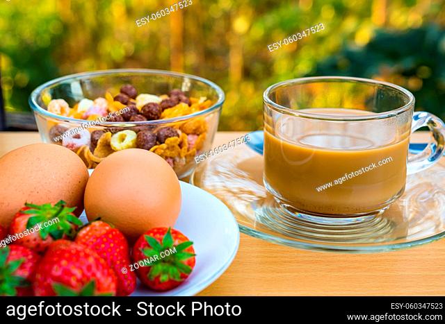 Hot coffee, cornflekes, boil eggs and ripe strawberry for breakfast