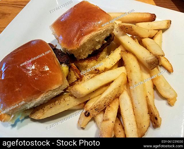 hamburgers with cheese on white plate with french fries