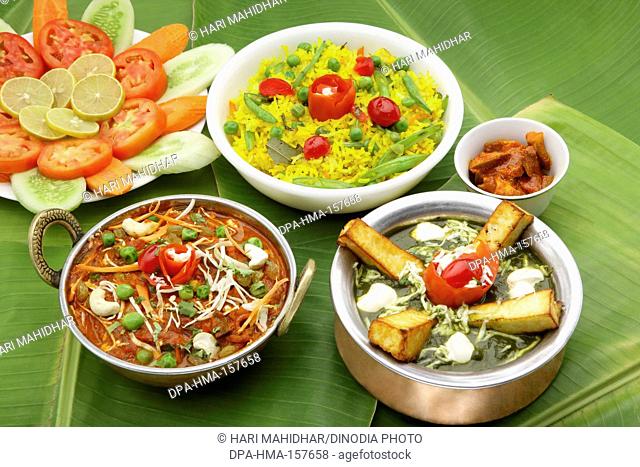 Food Indian , vegetarian kolhapuri in copper kadhai , palak paneer in copper handi , green peas rice pulao salad and mango pickle served on banana leaves