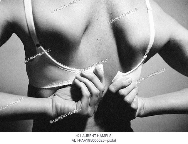 Woman fastening bra, rear view, close-up, b&w