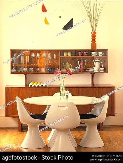 Retro style white dining table and chairs in front of wooden sideboard