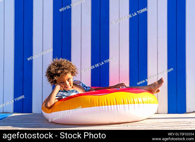 Cute boy sitting in multi colored inflatable doughnut